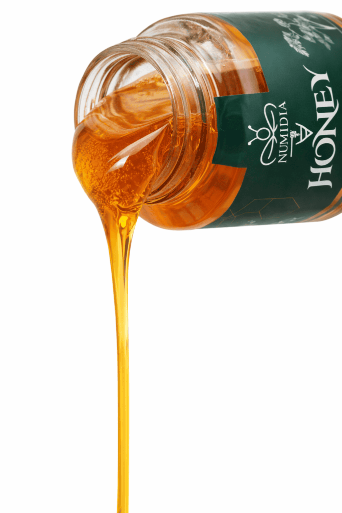 Golden British honey being poured from a Numidia Lancashire Local Honey jar, showing its naturally runny texture